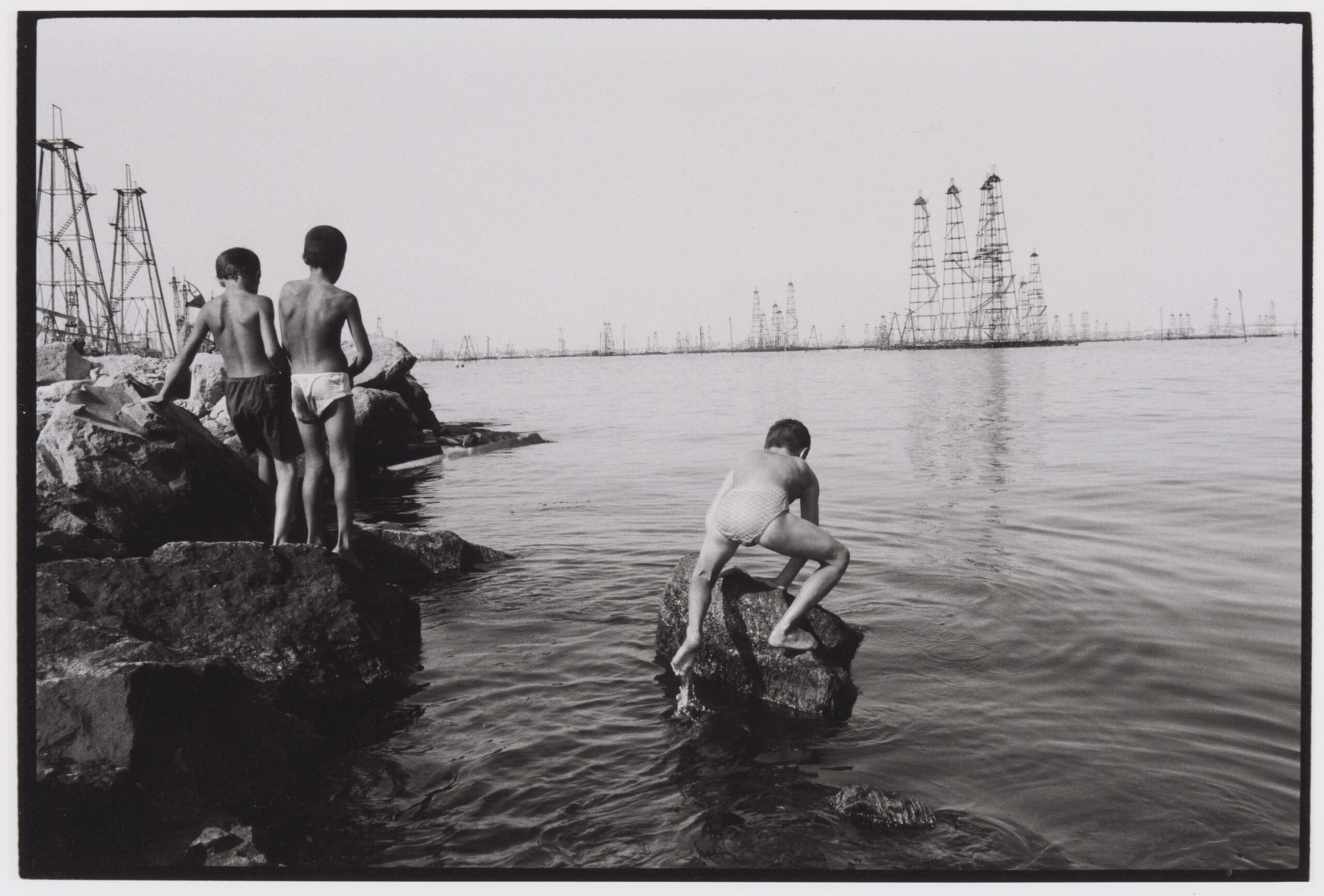 Enfants jouant dans les eaux de la mer Caspienne, non loin des plates-formes pétrolières de Bakou, Azerbaïdjan. Reportage « Enjeux du pétrole en mer Caspienne », 1998