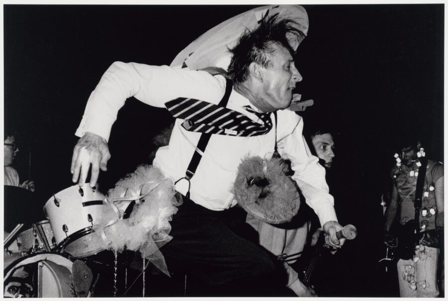 « Freddy [Fritz] Fox, le chanteur de The Mutants au Deaf Club sur Valencia Street, en 1979. The Mutants, qui étaient d’anciens élèves du San Francisco Art Institute, avaient étudié la photographie, la réalisation, la peinture et la sculpture. C’est un groupe important dans l’histoire du punk rock de San Francisco et de la new wave. Ils étaient connus pour leurs performances théâtrales qui incluaient souvent des accessoires raffinés, des projections et quelques singeries comiques. On dit souvent qu’ils sont l’un des premiers groupes “art-punk” de San Francisco. » 1979