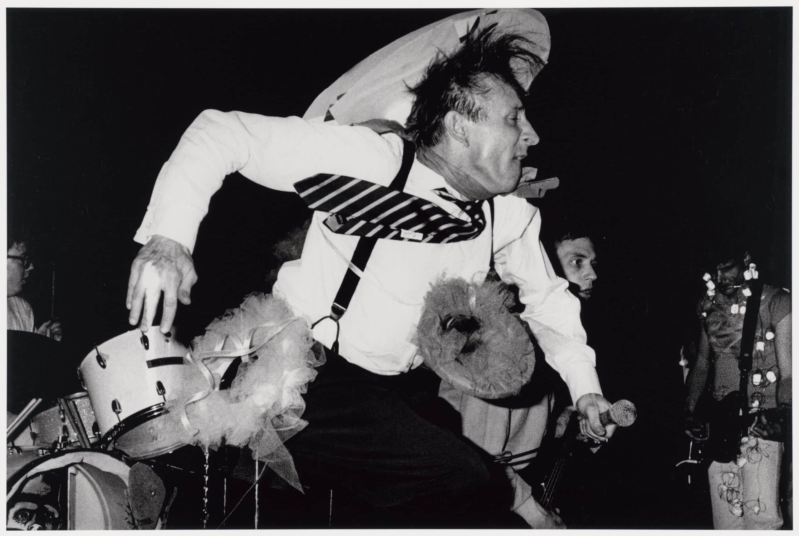 « Freddy [Fritz] Fox, le chanteur de The Mutants au Deaf Club sur Valencia Street, en 1979. The Mutants, qui étaient d’anciens élèves du San Francisco Art Institute, avaient étudié la photographie, la réalisation, la peinture et la sculpture. C’est un groupe important dans l’histoire du punk rock de San Francisco et de la new wave. Ils étaient connus pour leurs performances théâtrales qui incluaient souvent des accessoires raffinés, des projections et quelques singeries comiques. On dit souvent qu’ils sont l’un des premiers groupes “art-punk” de San Francisco. » 1979